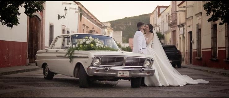 Ana y Rogelio junto a un auto clásico en una calle empedrada